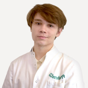 Der Mitarbeiter Noah Feix im weißen Apothekermantel.